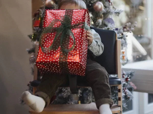 Baby in Abiie® high chair holding a wrapped present