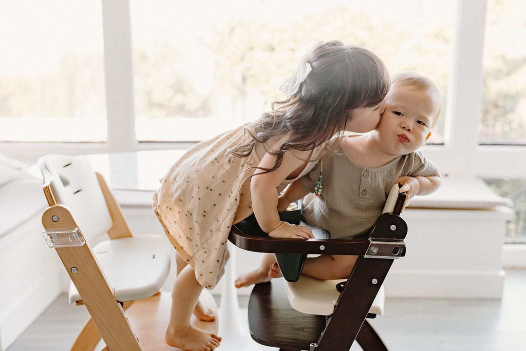 Toddler child kissing little brother in the best easy-clean high chair